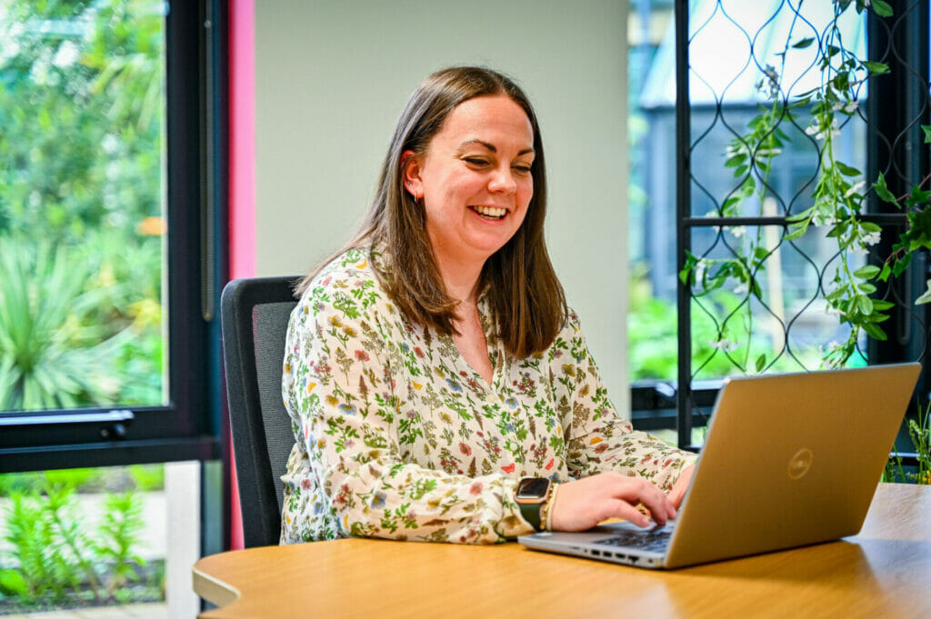 A woman working on a laptop at a desk.