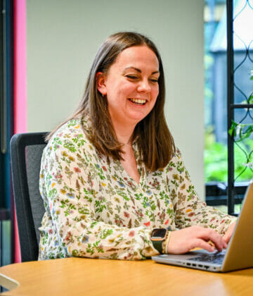 A woman working on a laptop at a desk.