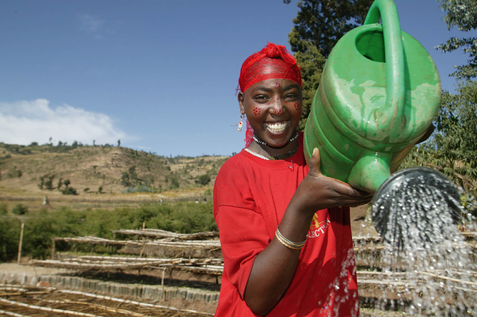 A lady watering plants and crops