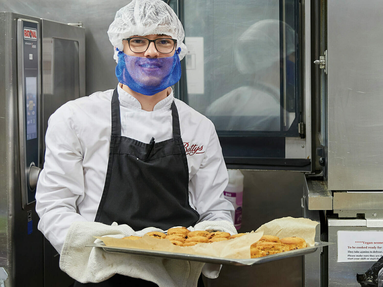 a man holding a tray of freshly baked goods in a bakery