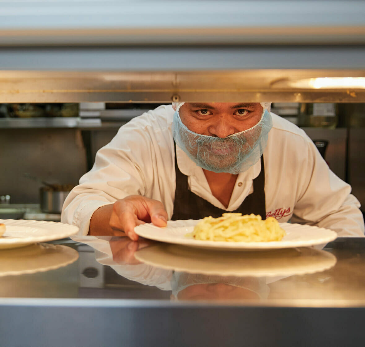 a chef delivering food onto the warming shelf