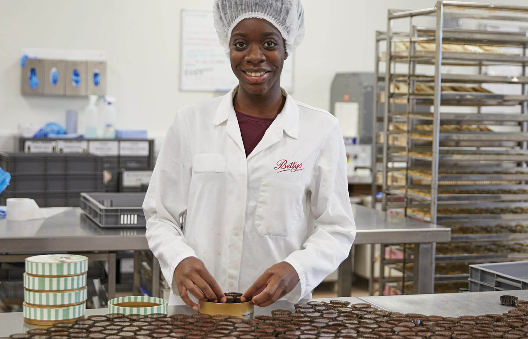 a woman smiling at the camera while packaging chocolate gifts