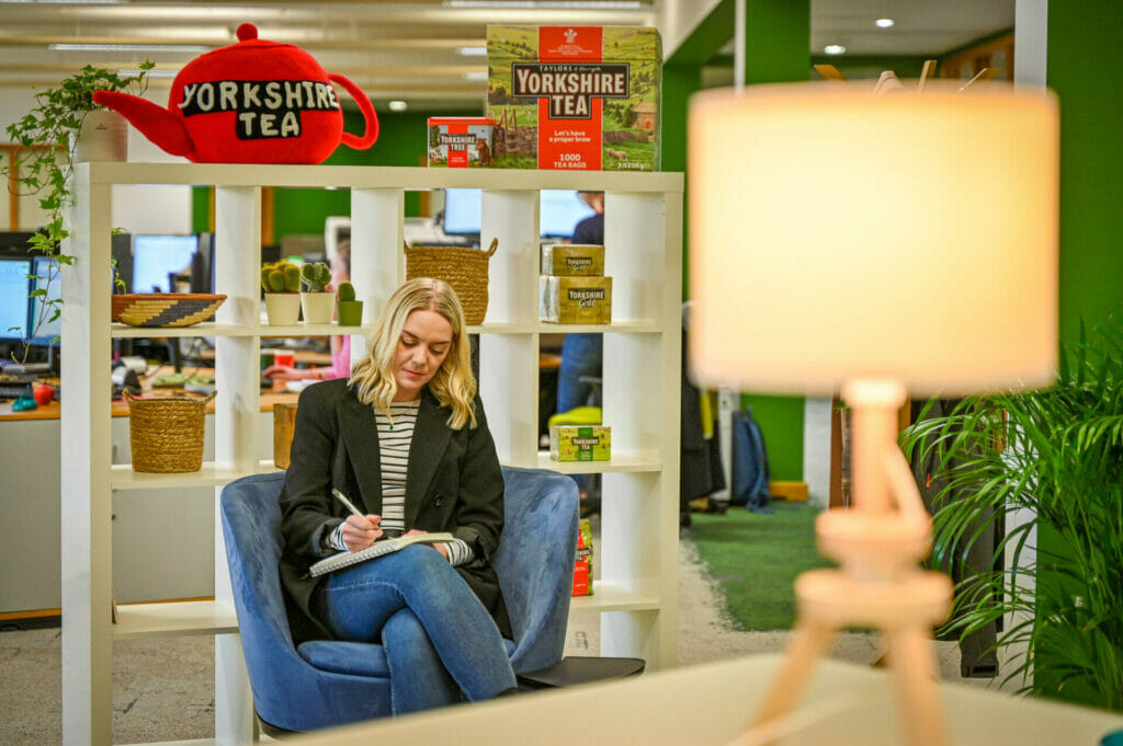 A photograph of a female writing in a notebook in a relaxed office setting