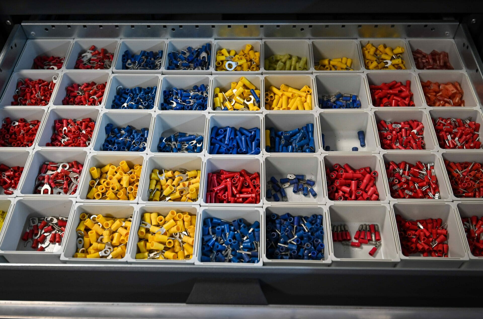 A drawer of coloured workshop accessories such as screws, washers, plugs