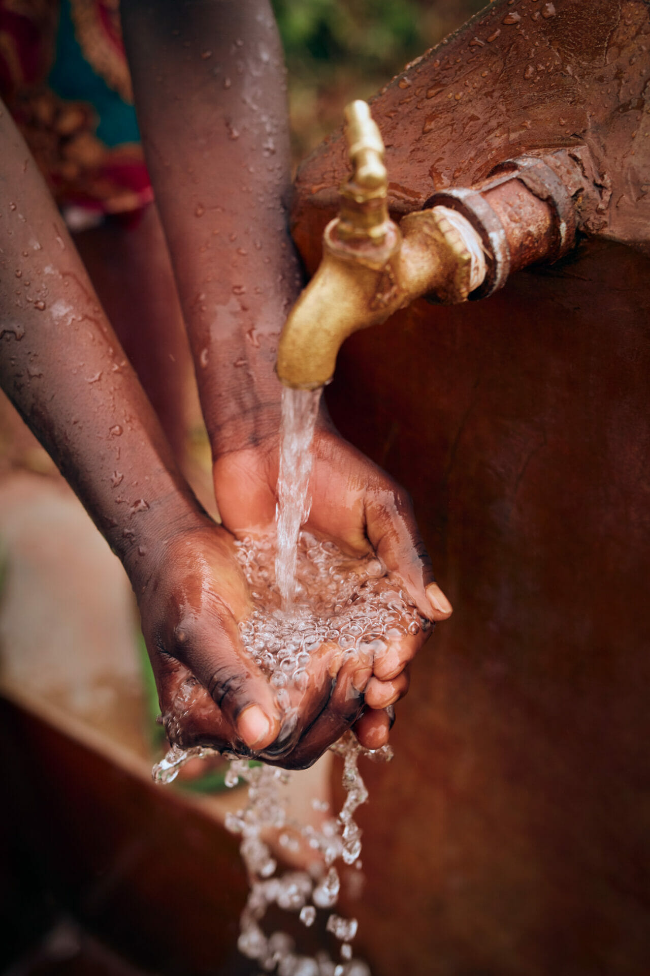 A photo of water pouring from a tap as someone washes their hands.