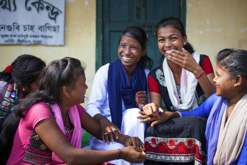 A group of young women and children chatting and laughing together.