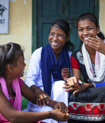 A group of young women and children chatting and laughing together.