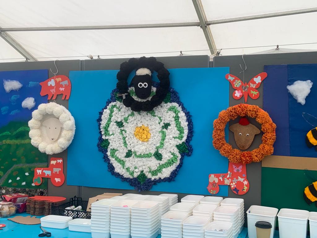A display of craft items at an agricultural show, with the white Yorkshire rose at the centre.